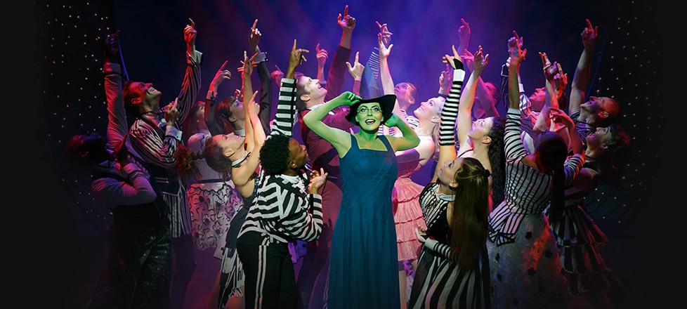 Elphaba Adjusting Witch Hat in the Midst of Dancing Shiz Students